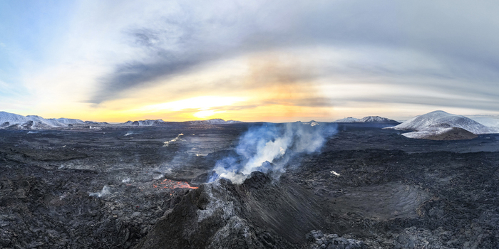 Aerial view of fiery lava erupts from a volcanic fissure contrasting against the stark snow dusted landscape under a vibrant sky Reykjavik Iceland.
