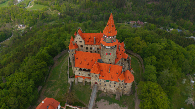 Aerial view of Bouzov Castle with its distinctive red tiled roofs and tall stone tower surrounded by a lush green forest in Bouzov Olomoucky kraj Czechia. Aerial view of Bouzov Castle with its distinctive red tiled roofs and tall stone tower surrounded by a lush green forest in Bouzov Olomoucky kraj Czechia.