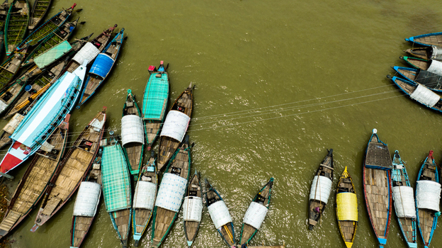 Aerial view of Baish Mowza Sarak Bazar with numerous wooden boats moored along the riverbank in Nabinagar Chittagong Division Bangladesh. Aerial view of Baish Mowza Sarak Bazar with numerous wooden boats moored along the riverbank in Nabinagar Chittagong Division Bangladesh.