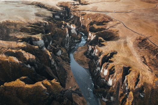 Aerial view of Fjadrargljufur canyon s dark river carves through the rugged landscape showcasing the sharp contrast between water and the earth Fjadrargljufur Iceland. Aerial view of Fjadrargljufur canyon s dark river carves through the rugged landscape showcasing the sharp contrast between water and the earth Fjadrargljufur Iceland.