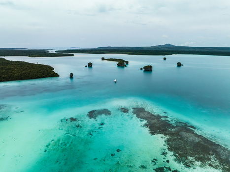 Aerial view of turquoise waters embracing rocky outcrops and reefs under a serene sky Pine Island L Île des Pins New Caledonia. Aerial view of turquoise waters embracing rocky outcrops and reefs under a serene sky Pine Island L Île des Pins New Caledonia.