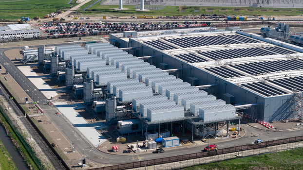 Aerial view of the industrial facility at Westpoort featuring rows of cooling units solar panels on the roof and wind turbines in the background Groningen Groningen Netherlands.
