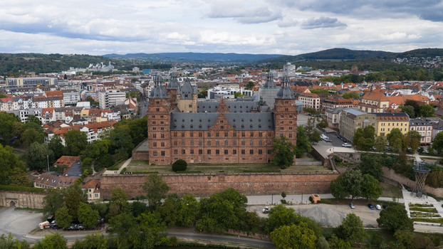 Aerial view of Schloss Johannisburg a historic red sandstone palace surrounded by lush trees and the cityscape of Aschaffenburg Bayern Germany.