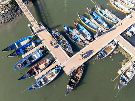 Aerial view of boats moored at Porta de Abrigo da Torreira their vibrant hulls contrasting with the calm murky water Torreira Aveiro Portugal. Aerial view of boats moored at Porta de Abrigo da Torreira their vibrant hulls contrasting with the calm murky water Torreira Aveiro Portugal.