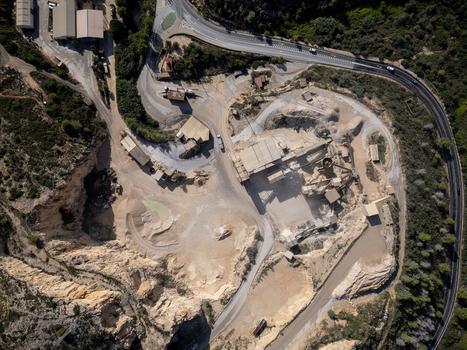 Aerial view of an industrial quarry site with processing facilities gravel piles and surrounding roads in Teulada Valencian Community Spain.
