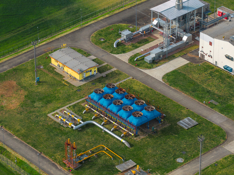 Aerial view of an industrial facility with blue cooling units yellow pipelines and technical buildings surrounded by green fields Hrusky South Moravian Region Czechia. Aerial view of an industrial facility with blue cooling units yellow pipelines and technical buildings surrounded by green fields Hrusky South Moravian Region Czechia.