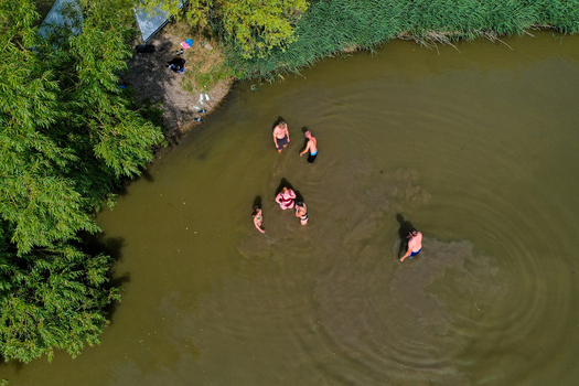 Herzogenaurach Germany 24 July 2025 Aerial view of people swimming in a lake during the Open Beatz Festival surrounded by lush green trees and reeds.