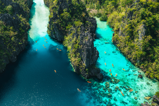 Aerial view of Big Lagoon with limestone cliffs and turquoise waters featuring people kayaking through the narrow channels El Nido Bay Philippines. Aerial view of Big Lagoon with limestone cliffs and turquoise waters featuring people kayaking through the narrow channels El Nido Bay Philippines.