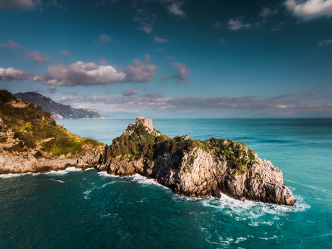 Aerial view of a rocky outcrop crowned with ancient ruins embraced by turquoise waters contrasting with the deep blue sea Amalfi Campania Italy. Aerial view of a rocky outcrop crowned with ancient ruins embraced by turquoise waters contrasting with the deep blue sea Amalfi Campania Italy.