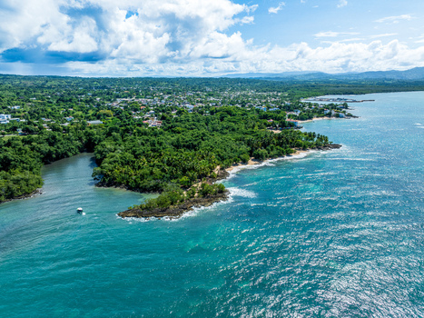 Aerial view of the coastline of Rio San Juan featuring lush tropical vegetation turquoise waters and a small boat near the shore in Rio San Juan Maria Trinidad Sanchez Dominican Republic. Aerial view of the coastline of Rio San Juan featuring lush tropical vegetation turquoise waters and a small boat near the shore in Rio San Juan Maria Trinidad Sanchez Dominican Republic.