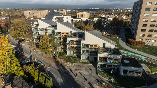 Aerial view of modern residential apartment buildings with slanted roofs and balconies surrounded by autumn trees and a road in Sweden. Aerial view of modern residential apartment buildings with slanted roofs and balconies surrounded by autumn trees and a road in Sweden.