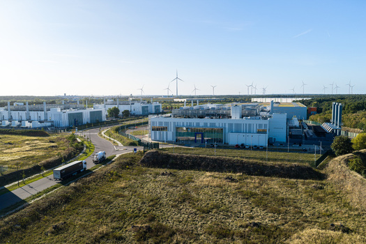 Aerial view of Vantage Data Centers BER1 complex featuring modern industrial buildings surrounding fields and wind turbines in Ludwigsfelde Brandenburg Germany. Aerial view of Vantage Data Centers BER1 complex featuring modern industrial buildings surrounding fields and wind turbines in Ludwigsfelde Brandenburg Germany.