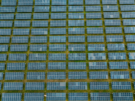 Aerial view of a large solar farm with rows of photovoltaic panels arranged in neat rows across a grassy landscape in Ogun State Nigeria.