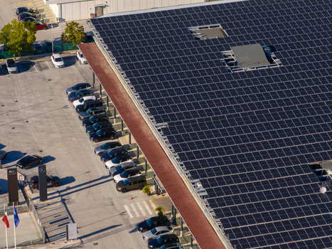 Aerial view of a commercial building roof covered with solar panels and a parking lot filled with cars in Ancona Marche Italy. Aerial view of a commercial building roof covered with solar panels and a parking lot filled with cars in Ancona Marche Italy.