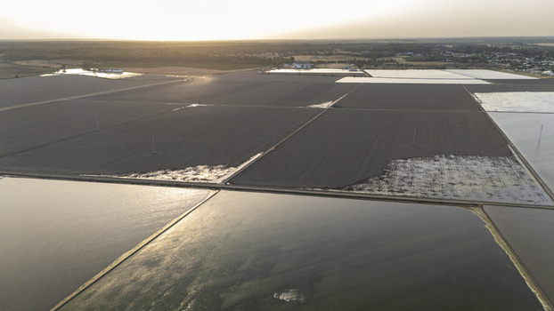 Aerial view of the flooded rice fields of Isla Minima with geometric patterns and golden sunset light over the horizon in Coria del Rio Andalusia Spain. Aerial view of the flooded rice fields of Isla Minima with geometric patterns and golden sunset light over the horizon in Coria del Rio Andalusia Spain.