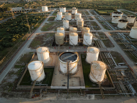 Aerial view of the Augusta oil refinery with large storage tanks and industrial infrastructure surrounded by green fields Augusta Sicily Italy. Aerial view of the Augusta oil refinery with large storage tanks and industrial infrastructure surrounded by green fields Augusta Sicily Italy.
