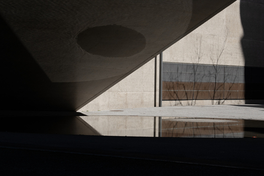 View of stark geometric shadows dance across textured concrete and still water reflecting a minimalist urban landscape in Zurich Switzerland. View of stark geometric shadows dance across textured concrete and still water reflecting a minimalist urban landscape in Zurich Switzerland.