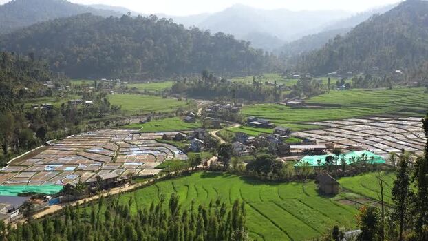 View of terraced fields and a village in a lush valley Nepal.