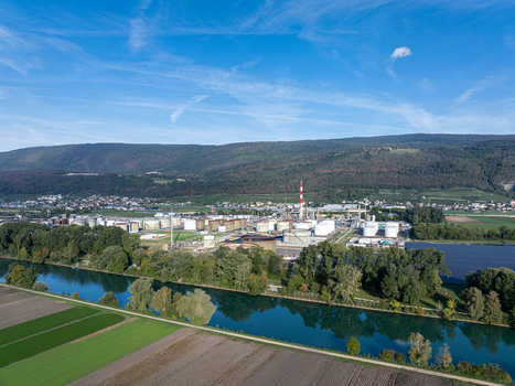 Aerial view of the Cressier Refinery featuring industrial storage tanks and a tall chimney situated near a river and agricultural fields in Cornaux Neuchatel Switzerland. Aerial view of the Cressier Refinery featuring industrial storage tanks and a tall chimney situated near a river and agricultural fields in Cornaux Neuchatel Switzerland.