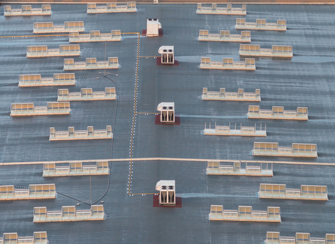 Aerial view of a modern industrial warehouse roof featuring a symmetrical arrangement of rooftop HVAC units ventilation systems and skylights Alixan Auvergne Rhone Alpes France.