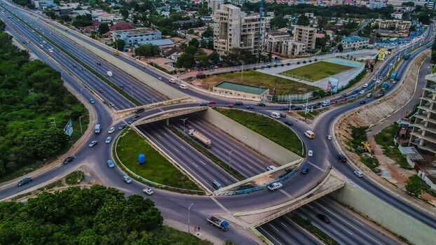Aerial view of a highway interchange with multi lane roads concrete overpasses and surrounding urban development in Ghana. Aerial view of a highway interchange with multi lane roads concrete overpasses and surrounding urban development in Ghana.