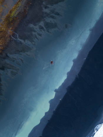 Aerial view of a glacial river flowing through a volcanic landscape with dark sand banks and turquoise water in Iceland. Aerial view of a glacial river flowing through a volcanic landscape with dark sand banks and turquoise water in Iceland.