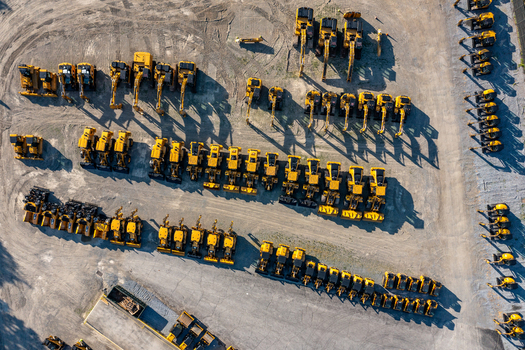 Aerial view of rows of yellow construction excavators parked in a large dirt lot with long shadows in LaGrange New York United States. Aerial view of rows of yellow construction excavators parked in a large dirt lot with long shadows in LaGrange New York United States.