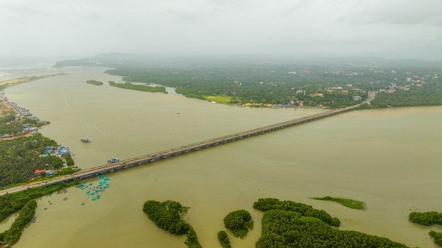 Aerial view of the long bridge spanning the Sharavathi River surrounded by lush green mangroves and coastal vegetation in Honnavar Karnataka India.