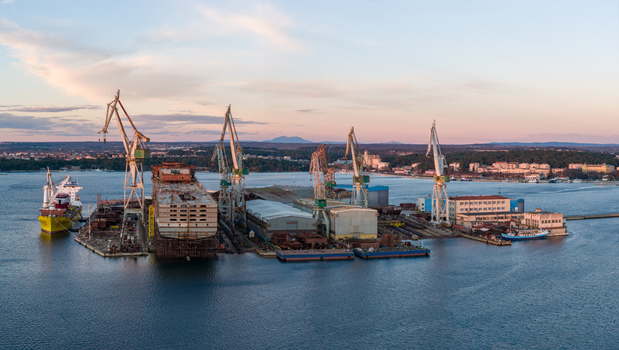Aerial view of Uljanik Shipyard with towering cranes industrial structures and ships under construction along the waterfront in Pula Croatia. Aerial view of Uljanik Shipyard with towering cranes industrial structures and ships under construction along the waterfront in Pula Croatia.