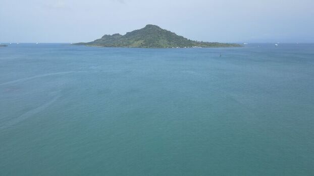 Aerial view of a lush green island surrounded by calm blue sea waters near the coast of Bakauheni Lampung Indonesia.