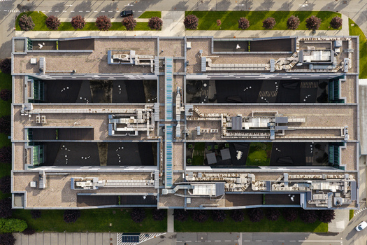 Aerial view of a modern production company office building with complex rooftop HVAC systems and internal courtyards in Masovian Voivodeship Poland.