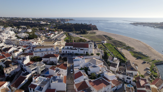 Aerial view of the historic village of Ferragudo featuring the white church terracotta roofed houses and the scenic Arade river estuary Ferragudo Faro District Portugal.
