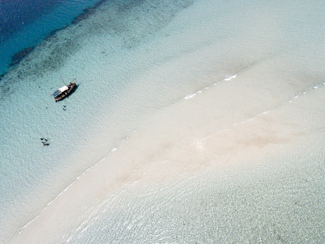 Aerial view of a traditional dhow boat near a white sandbar in the turquoise waters of Kisite Mpunguti Marine National Park in Kwale Kwale County Kenya. Aerial view of a traditional dhow boat near a white sandbar in the turquoise waters of Kisite Mpunguti Marine National Park in Kwale Kwale County Kenya.