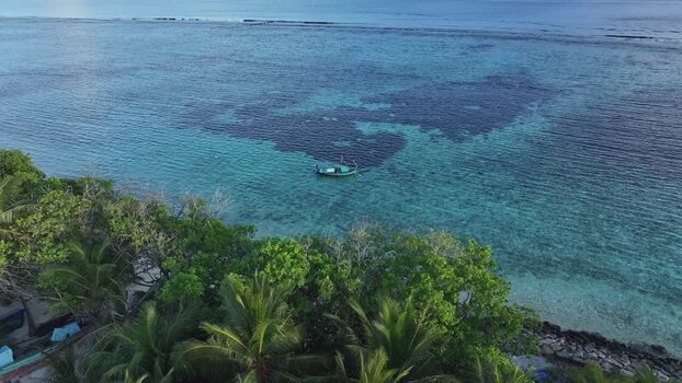 Aerial view of a boat in turquoise water near palm trees Maldives. Aerial view of a boat in turquoise water near palm trees Maldives.