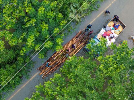 Banshkhali Upazila Chittagong Division Bangladesh 10 July 2026 Aerial view of a flooded road with people on a bamboo raft and a truck navigating through high water. Banshkhali Upazila Chittagong Division Bangladesh 10 July 2026 Aerial view of a flooded road with people on a bamboo raft and a truck navigating through high water.