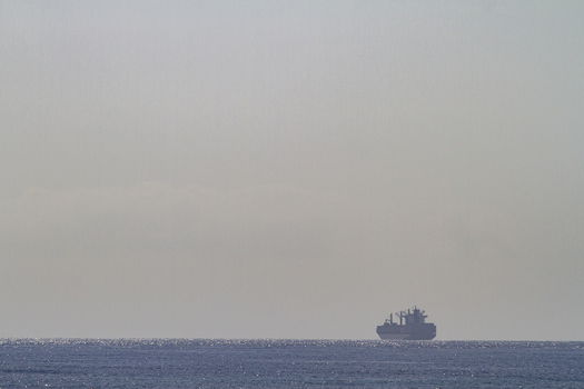 View of a large container ship sailing on the horizon of the Indian Ocean under a hazy sky near Tiwi Beach in Tiwi Wilaya ya Kwale Kenya. View of a large container ship sailing on the horizon of the Indian Ocean under a hazy sky near Tiwi Beach in Tiwi Wilaya ya Kwale Kenya.
