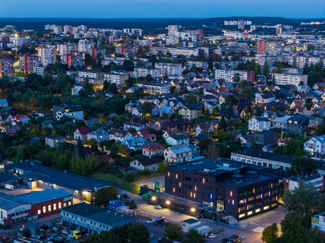 Aerial view of Vilnius at twilight featuring a modern office building with illuminated windows surrounded by residential houses and urban infrastructure in Vilnius Vilnius County Lithuania. Aerial view of Vilnius at twilight featuring a modern office building with illuminated windows surrounded by residential houses and urban infrastructure in Vilnius Vilnius County Lithuania.