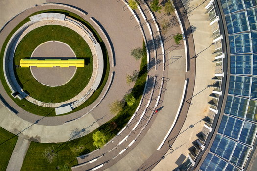 Aerial view of a modern circular plaza with a bright yellow bench concentric stone pathways green lawns and a large glass roofed building in Belgrade City of Belgrade Serbia. Aerial view of a modern circular plaza with a bright yellow bench concentric stone pathways green lawns and a large glass roofed building in Belgrade City of Belgrade Serbia.