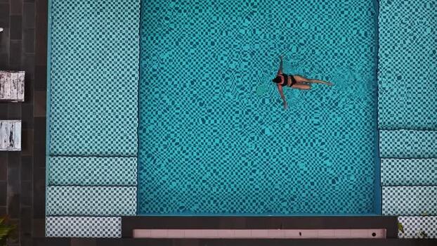 Aerial view of a person swimming in a turquoise pool Indonesia.
