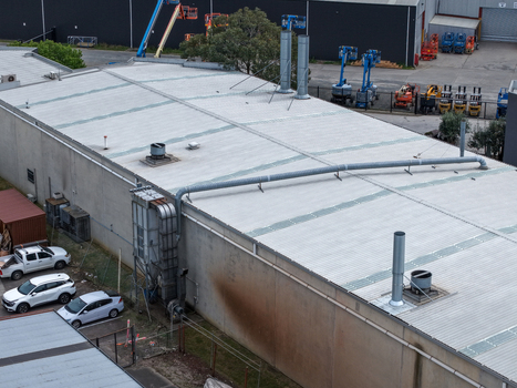 Melbourne VIC Australia 25 September 2026 Aerial view of an industrial factory building featuring metal roofing ventilation systems and a parking area with vehicles.