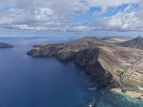 Aerial view of the rugged coastline and cliffs at Ponta da Calheta featuring turquoise waters rocky terrain and a coastal road in Porto Santo Madeira Portugal. Aerial view of the rugged coastline and cliffs at Ponta da Calheta featuring turquoise waters rocky terrain and a coastal road in Porto Santo Madeira Portugal.