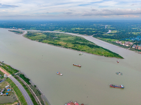 Aerial view of Char Bakalia island surrounded by the river with cargo ships navigating the waters and a road along the bank in Chittagong District Chittagong Division Bangladesh.