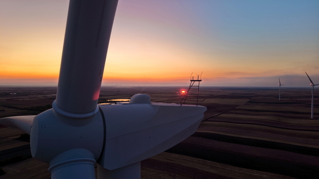 Aerial view of wind turbines standing in the vast fields during a vibrant sunset with golden light illuminating the horizon in Vladimirovac Vojvodina Serbia. Aerial view of wind turbines standing in the vast fields during a vibrant sunset with golden light illuminating the horizon in Vladimirovac Vojvodina Serbia.