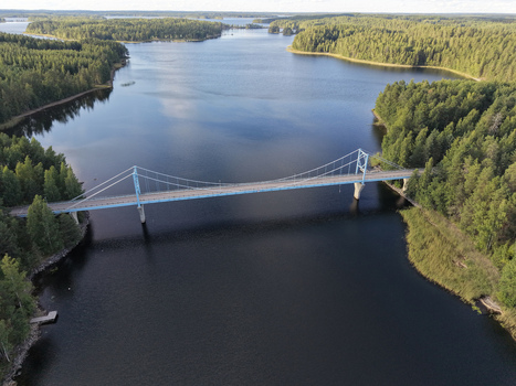 Aerial view of Potkusalmen silta Bridge spanning over the calm waters of a lake surrounded by dense pine forests in Savonlinna Etela Savo Finland.
