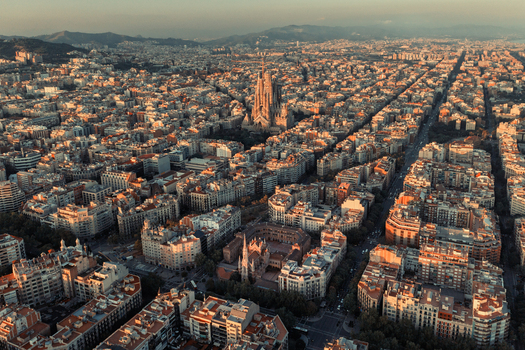 Aerial view of the Sagrada Familia basilica surrounded by the dense urban grid and historic architecture of the city during golden hour in Barcelona Catalonia Spain. Aerial view of the Sagrada Familia basilica surrounded by the dense urban grid and historic architecture of the city during golden hour in Barcelona Catalonia Spain.