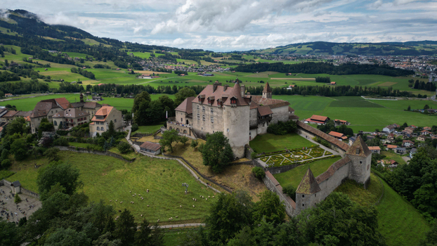 Aerial view of the medieval Gruy&egrave;res Castle standing majestically on a hill its stone walls contrasting with the lush green fields Gruy&egrave;res Fribourg Switzerland.