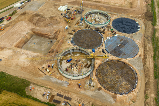 Aerial view of a construction site with large circular concrete foundations heavy machinery and a yellow tower crane in Lithuania. Aerial view of a construction site with large circular concrete foundations heavy machinery and a yellow tower crane in Lithuania.