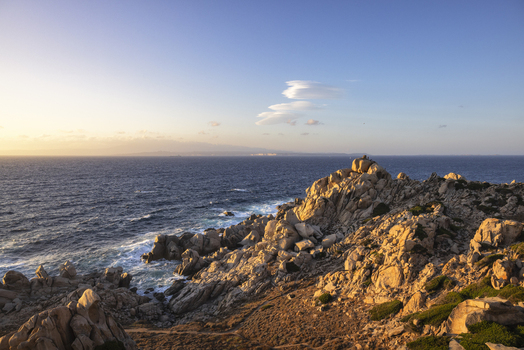 View of granite rock formations of Capo Testa overlooking the Mediterranean Sea during sunset with soft golden light and blue sky Capo Testa Sardegna Italy.