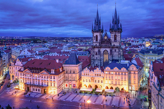 Aerial view of the Church of Our Lady before Tyn with its iconic spires overlooking the historic Old Town Square at dusk surrounded by illuminated buildings in Prague Prague Czechia. Aerial view of the Church of Our Lady before Tyn with its iconic spires overlooking the historic Old Town Square at dusk surrounded by illuminated buildings in Prague Prague Czechia.