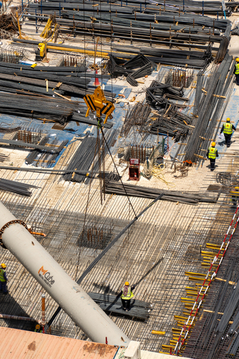 Aerial view of a busy construction site with workers installing steel rebar reinforcement and heavy machinery in Dubai Dubai United Arab Emirates. Aerial view of a busy construction site with workers installing steel rebar reinforcement and heavy machinery in Dubai Dubai United Arab Emirates.